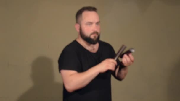 One Man With A Beard in Black T-Shirt, Playing on the Percussion Instrument Claves. sullo sfondo delle mura luminose . — Video Stock