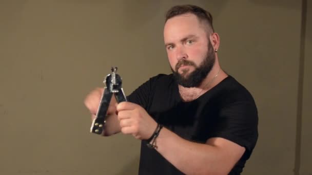 One Man With a Beard in Black T-Shirt, Playing on the Percussion Instrument Ratchet. on the Bright Walls Background. — Stock Video