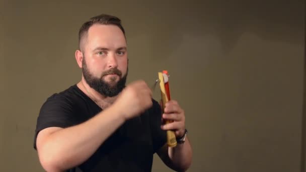 One Man With a Beard in Black T-shirt, Jogando no instrumento de percussão catraca. no fundo das paredes brilhantes . — Vídeo de Stock