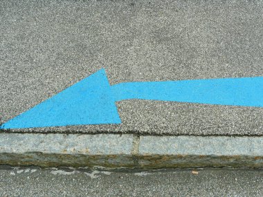 Mavi ok asfaltta solu işaret ediyor yön bulma ve yol bulma için zemin işareti olarak. Kopyalama alanı.