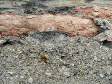 Kırmızı tuğlalı, sert havan topu ve görünür katmanlı yıpranmış duvarın detayları.