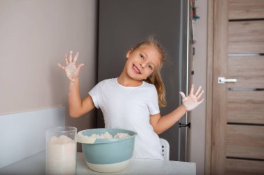 Un kaplı küçük kız mutfakta yemek pişiriyor ve eğleniyor..