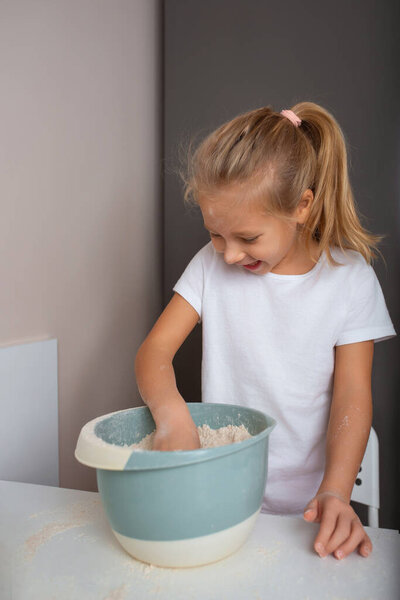 Little girl preparing dough, mixing flour in the kitchen