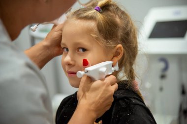 Mutlu bir kız özel bir aletle kuaförde kulaklarını deldirir. Acısız işlem.