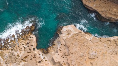 Gök mavisi deniz kayalık kıyı şeridini yıkıyor. Hava aracı görüntüsü. Tatil kavramı.