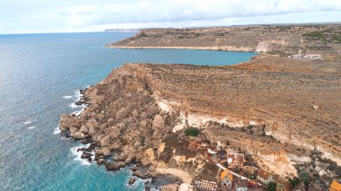 Kayalıklar boyunca geleneksel binalarla Malta kıyı şeridinin havadan görünüşü.