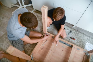 Baba ve oğul evlerinde yeni bir paket masası kuruyorlar..