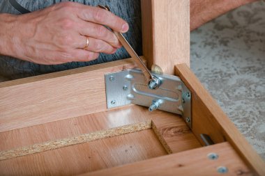 Adam ingiliz anahtarı kullanarak mobilya monte ediyor. DIY ev onarımı.