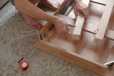 Adam evde tahta masa bacakları monte ediyor. DIY mobilya projesi.