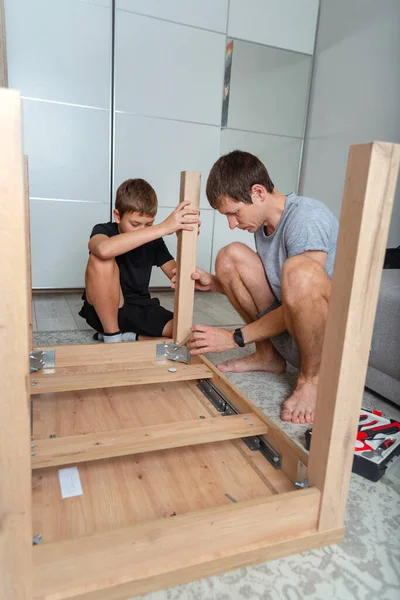 Baba ve oğul evde ahşap bir masa kuruyorlar..