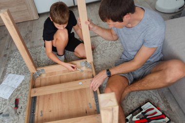 Baba ve oğul evde mobilya montajı yapıyorlar, DIY projesinde birlikte çalışıyorlar..