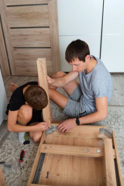 Baba ve oğul evde mobilya montajı yapıyor..