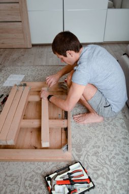 Adam evde mobilya montajı yapıyor. DIY projesi.