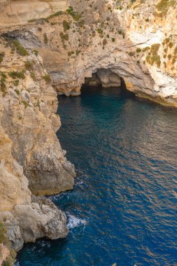 Doğal bir deniz mağarası, engebeli kireçtaşı kayalıkları ve derin mavi suların yer aldığı çarpıcı Akdeniz kıyı manzarası. Seyahat blogları, turizm pazarlama ve yaz tatili reklamları için ideal.
