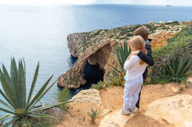 Kardeşler Malta 'daki ikonik Mavi Grotto deniz kemerine hayran kaldılar. Seyahat pazarlaması, aile tatil blogları ve tarihi yerleri gösteren Akdeniz turizm broşürleri için ideal.
