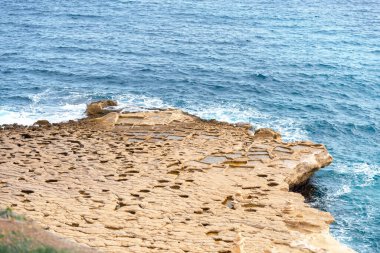 Malta sahilinde kireçtaşı kayalara oyulmuş geleneksel tuz tavaları. Seyahat blogları, Akdeniz turizm pazarlaması ve tarihi doğa içeriği için mükemmel.