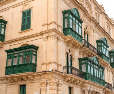 Malta 'nın Valletta kentinin mimari çekiciliğini keşfedin, tarihi kireçtaşı binalardaki ikonik yeşil ahşap balkonlar. Seyahat pazarlama ve kültürel içerik için ideal.