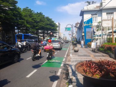 Bandung, Endonezya - 13 Ekim 2025: Motosikletler ve yayalarla dolu şehir caddesi