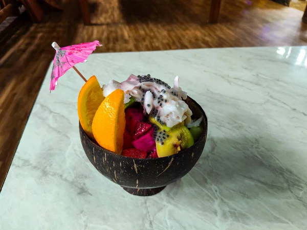 Karışık buzlu tatlı ve meyveli şekerleme bir restoranda hindistan cevizi kasesinde servis ediliyor.