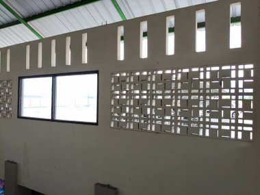 İki büyük penceresi ve birkaç havalandırma deliği olan bir duvar.