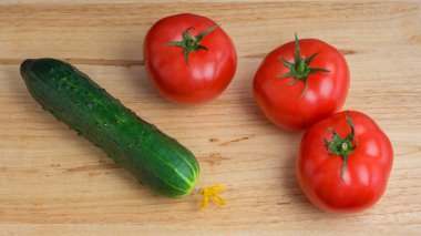 Tahta zemin üzerinde olgun domates ve salatalık.