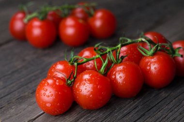 Bir demet olgun kırmızı kiraz domatesleri ahşap arka planda yakın plan