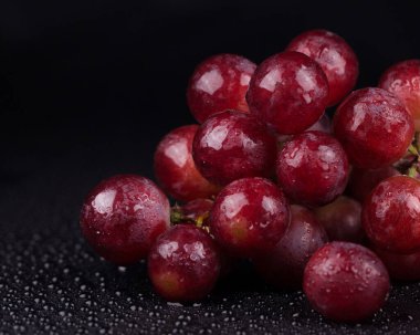 Siyah arkaplanda sulu kırmızı üzümler..