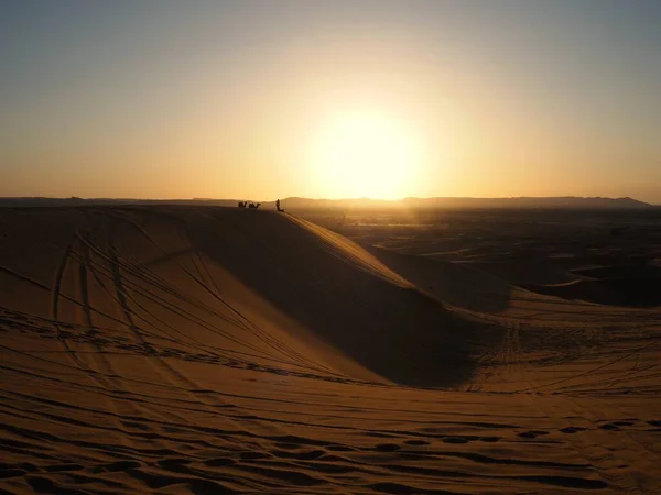 Camel silhouettes among the orange sand dunes of the Merzouga Desert at sunset. Sahara Desert Landscapes, Travel to Morocco.