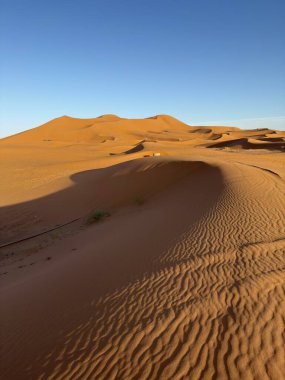Güneş batarken Merzouga Çölü 'nün turuncu kum tepeleri. Kumun üzerindeki dalgaların dokusu. Çöl manzarası. Fas 'a seyahat, Sahra Çölü, Erg Chebbi kumulları.