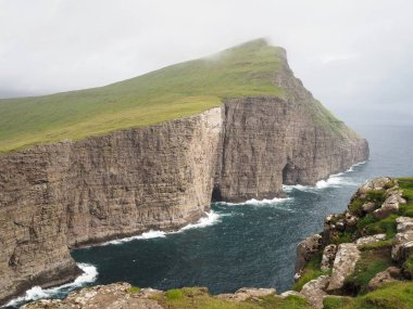 Faroe Adaları 'nın yeşil kuzey manzaraları. Traelanipa sarp kayalıklarının dramatik manzarası mavi Atlantik Okyanusu 'nun üzerinde yükseliyor. Vagar Adası.