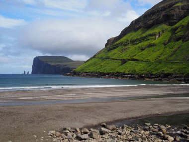 Faroe Adaları 'nın yemyeşil kuzey manzaraları. Tjornuvik köyünde, Streymoy Adası 'ndaki yeşil yamaçların altında yer alan resimli siyah kum plajı..
