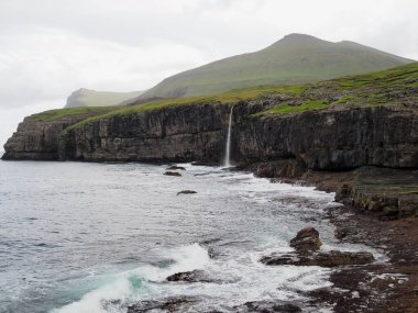 Faroe Adaları 'nın yeşil kuzey manzaraları. Molin şelalesi Atlantik Okyanusu 'nun ortasındaki Eysturoy Adası' na dökülüyor..