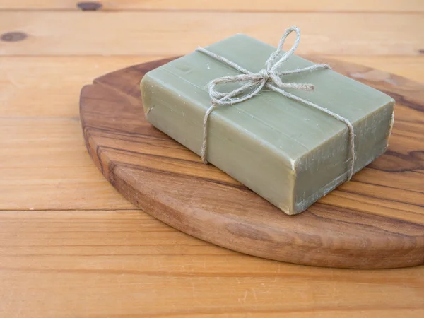 Soap bar tied with jute rope on the olive tree textured board