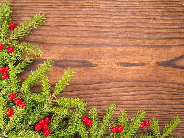 Vánoční stromek větve a červené bobule na tmavém pozadí — Stock fotografie