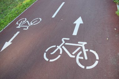 Kırmızı Asfaltta Beyaz Bisiklet Yolu İşareti ve Yön Oku