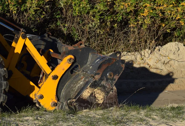 Buldozer güneşli bir sonbahar gününde deniz kıyısında çalışıyor.
