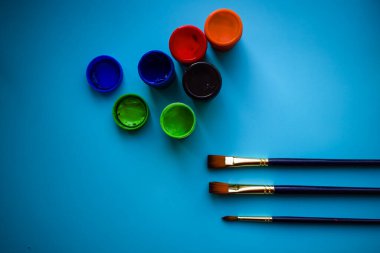 Yaratıcı İlham: Profesyonel Sanatsal Fırçalar ve Parlak Mavi Üzerine Canlı Gouache Boya Kavanozları.