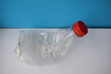 Çevre dostu bilinç: Mavi ve Beyaz Arkaplan Geri Dönüşüm Konsepti İçin Buruşmuş Plastik Süt Şişesi.