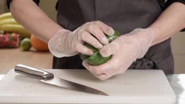 Kadının elleri avokado ve sebzeleri ikiye bölüyor.