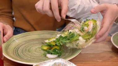 Genç adam kız arkadaşına salata yapıyor.