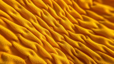 Belirgin bir dokusu ve yoğun dokuması olan canlı sarı bir kumaşın makro görüntüsü. Yüzey tekrar eden kıvrımlar oluşturur, soyut ve dinamik bir model yaratır. Tekstil ve tasarım projeleri için ideal.