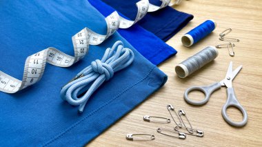 Hafif ahşap arka planda özel dikim ve kıyafet değişiklikleri. Moda, hassasiyet, kalite ve detaylara olan ilginin görsel bir temsili.