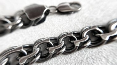 Yumuşak bir ışık arka planında kendine özgü dokuması olan gümüş bir zincirin detaylı bir yakın çekimi. Tasarım, reklam, arkaplan ve güç ve güvenilirlik kavramları için soyut metalik doku.