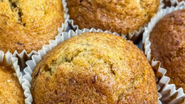 Kağıt bardaklarda ev yapımı keklerin yakın çekimi, farklı yüzey dokusuna sahip altın kahverengi pastalar..