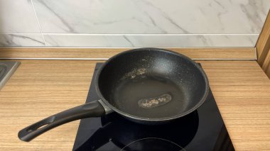 Yıpranmış bir tava ve mutfak sobasında hasarlı bir yapışmaz kaplama. Evdeki aşınma ve yıpranmayı kavramsallaştırmak, yemek takımlarını değiştirmek ve evde yemek pişirme güvenliğini sağlamak..