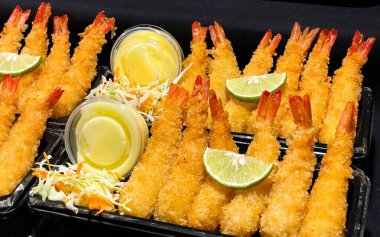 Limon dilimleri, sos ve taze sebze garnitürle servis edilen kızarmış karides. Konteynırda Asya usulü lezzetli bir aperatif. Fast food, sokak yemeği ve restoran kullanımı için uygun.