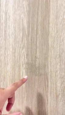Ahşap görünümlü bir mobilyanın dış panelindeki küf lekelerini gösteren yakın plan bir el. Kalıba yüksek nem ve kötü iklim neden olmuş..