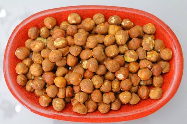 Beyaz arka planda kırmızı kasede fındıklar, üst manzara.