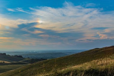 a beautiful shot of a field with a cloudy sky during sunset