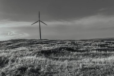 windmill and power lines in the field in the mountains